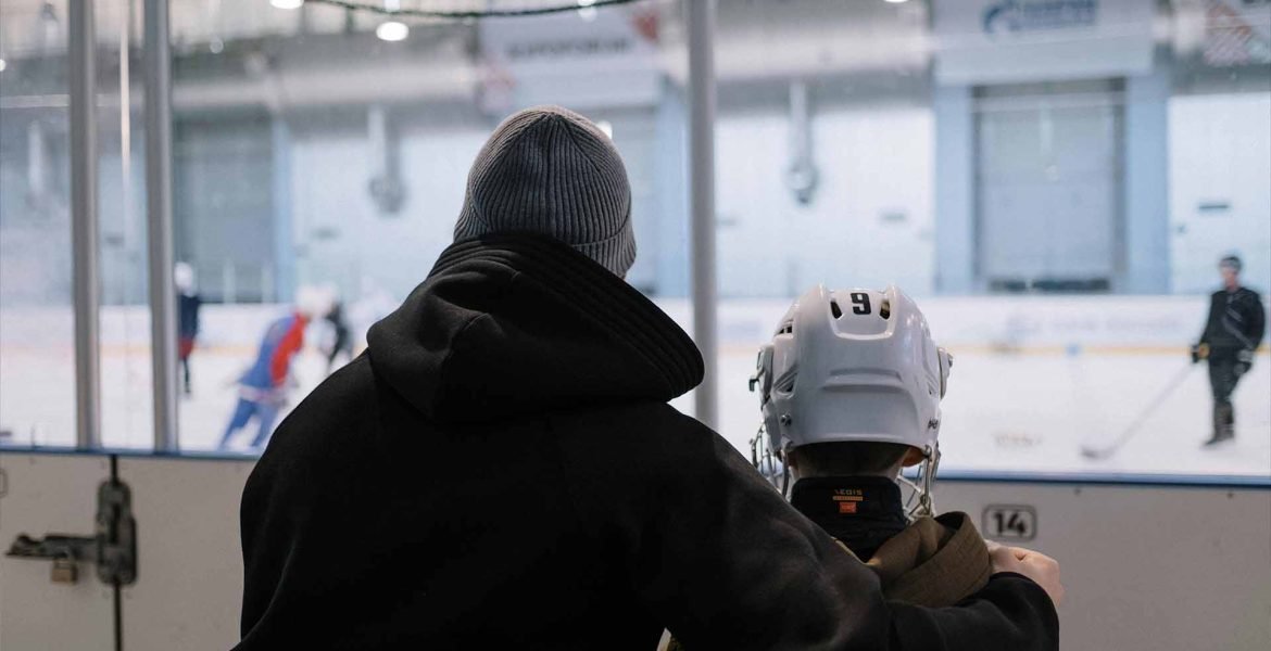 dad sitting with his child on the bench watching other skater at the arena